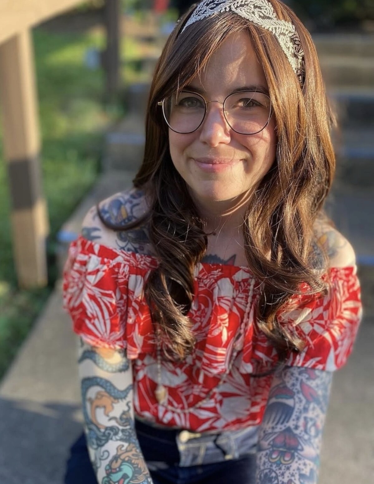 Katie Lee smiling, with her colorful tattoo sleeves visible